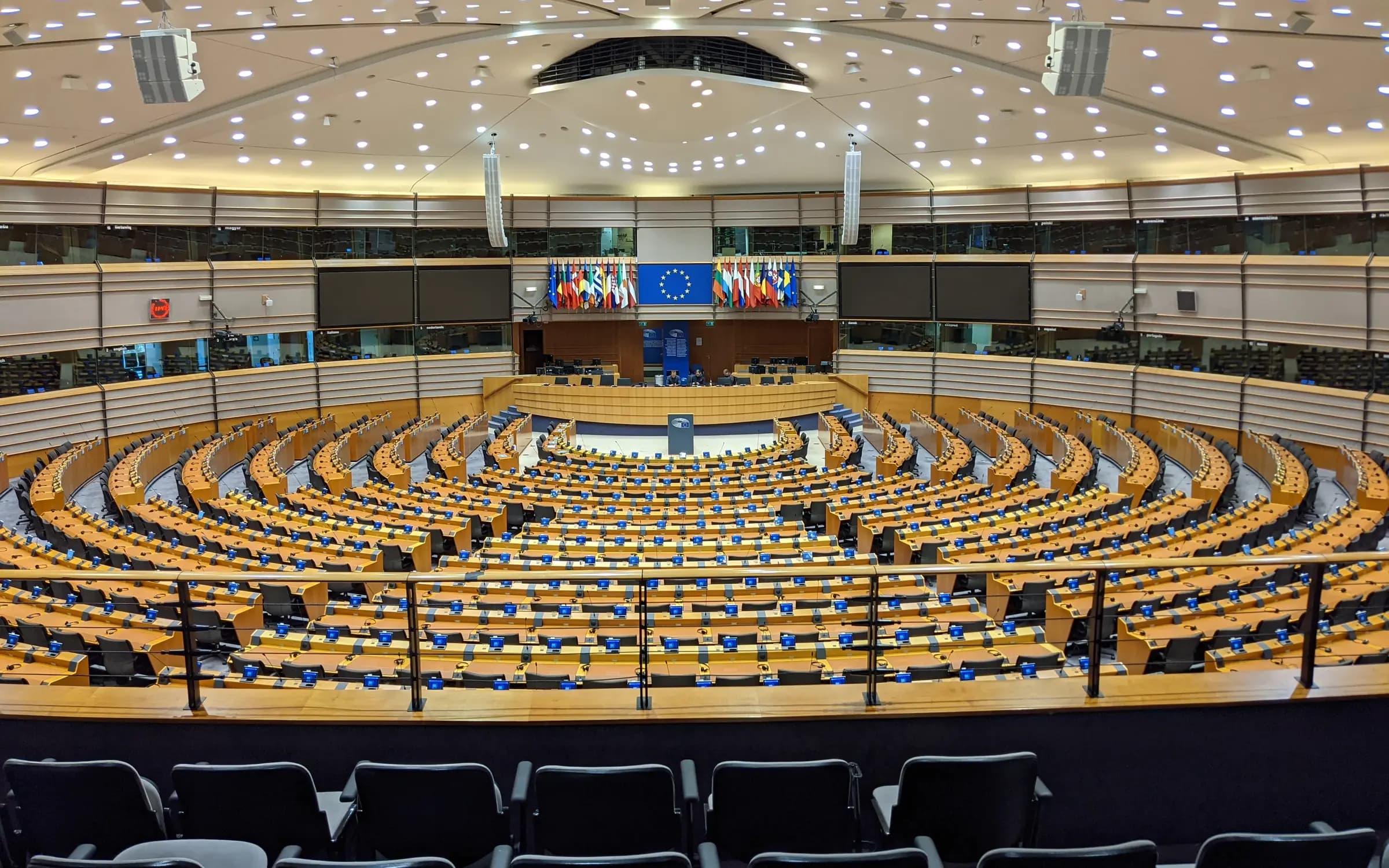 L'emiciclo del Parlamento europeo a Bruxelles, vuoto, con le bandiere dell'Unione e degli Stati membri sul fondo